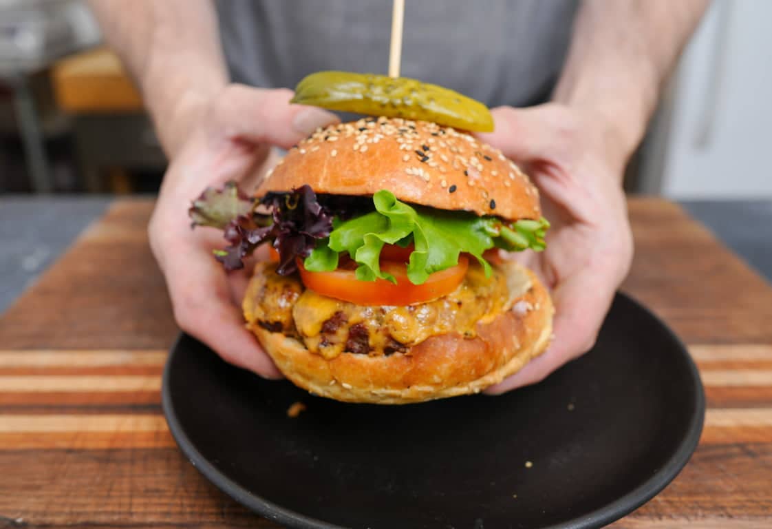 a hand holding a burget bun with burger