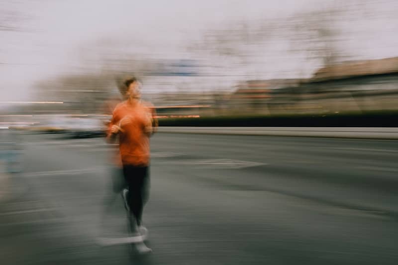 A person running on a street with motion blur.