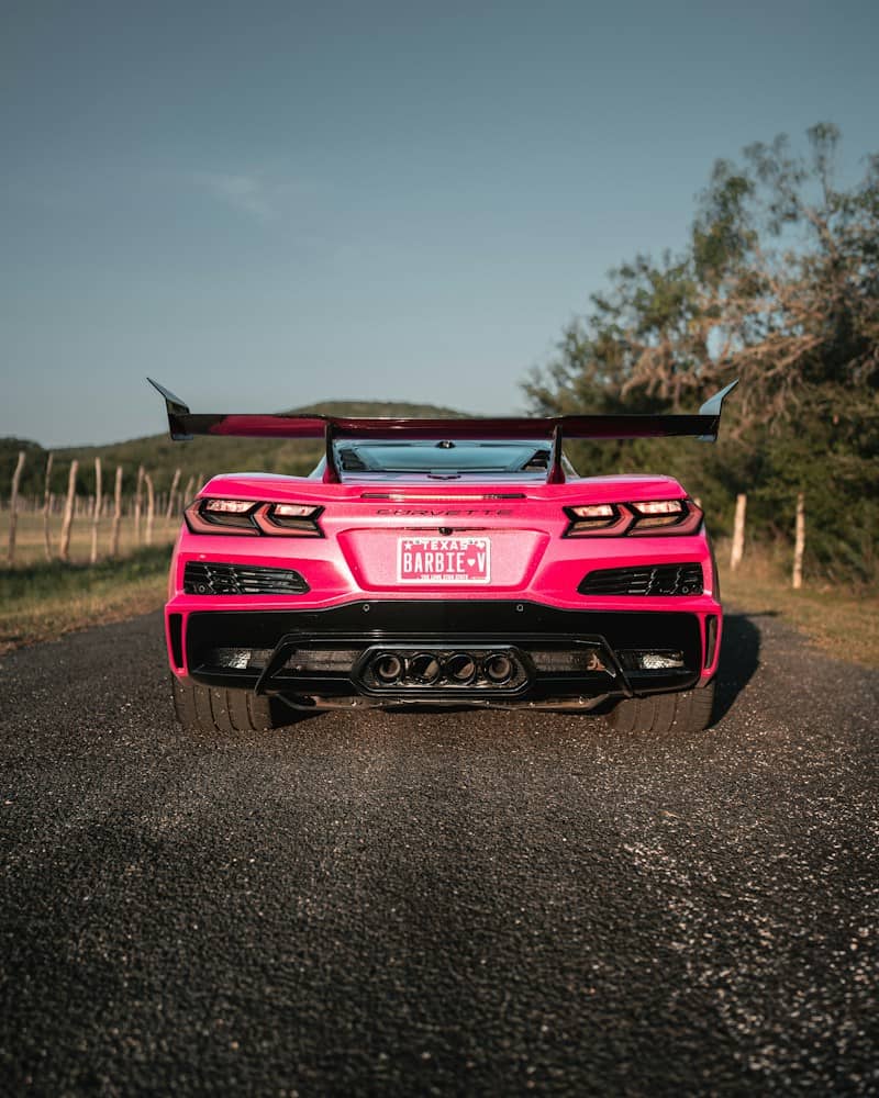 A bright pink sports car with Barbie license plate