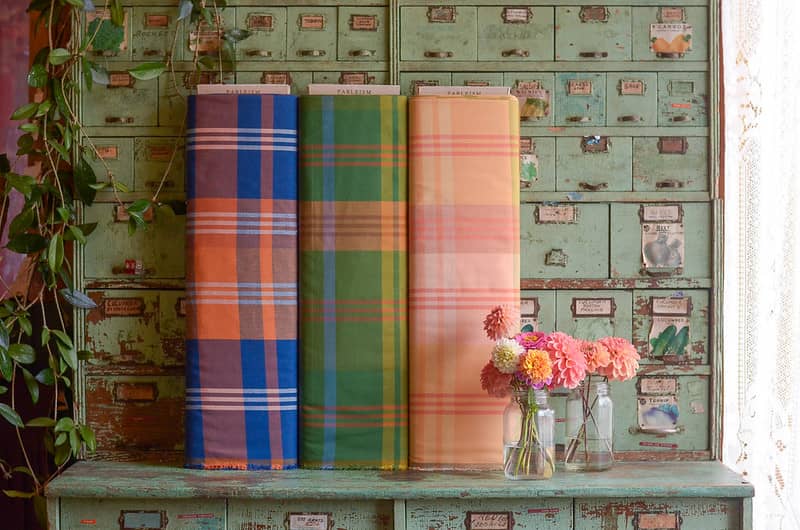 Three Plaid bolts of fabric on a vintage seed cabinet