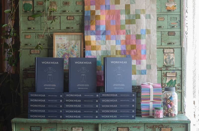 Workwear books stacked on a vintage seed cabinet