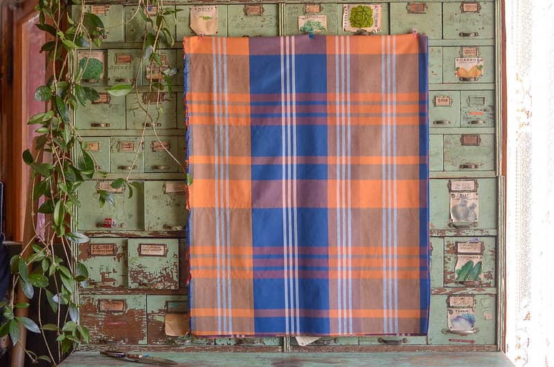 Fableism Plaid fabric hanging on a vintage seed cabinet