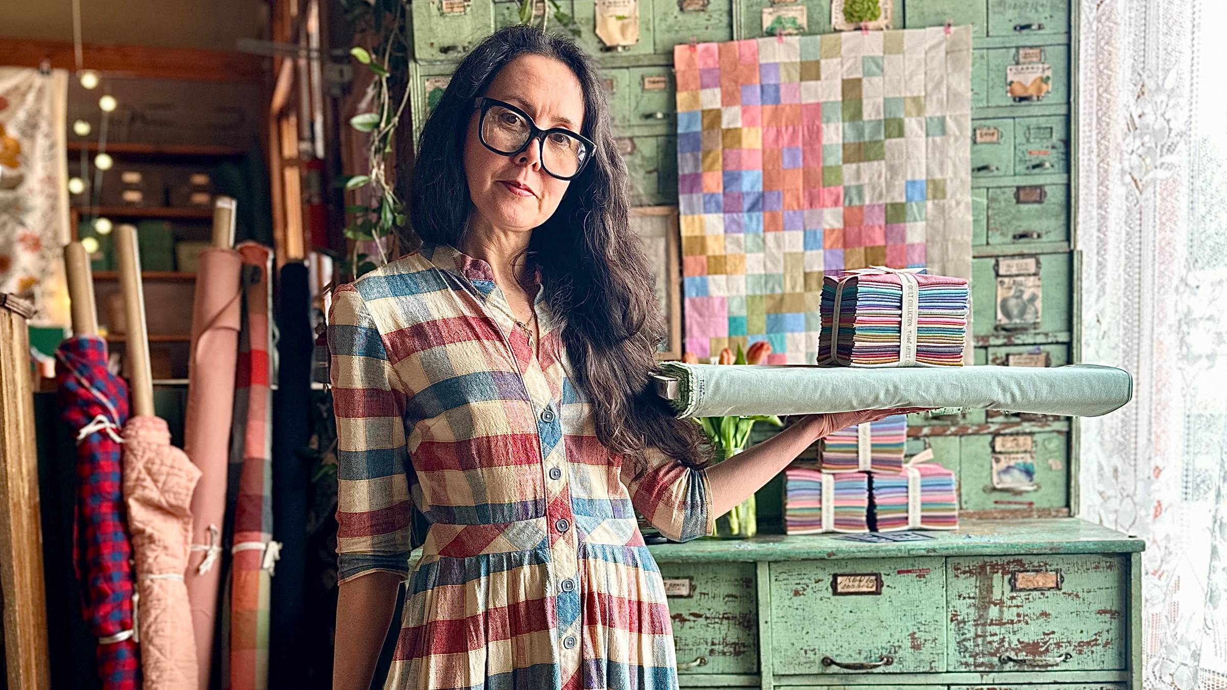 Karyn holding a bolt of fabric and a bundle