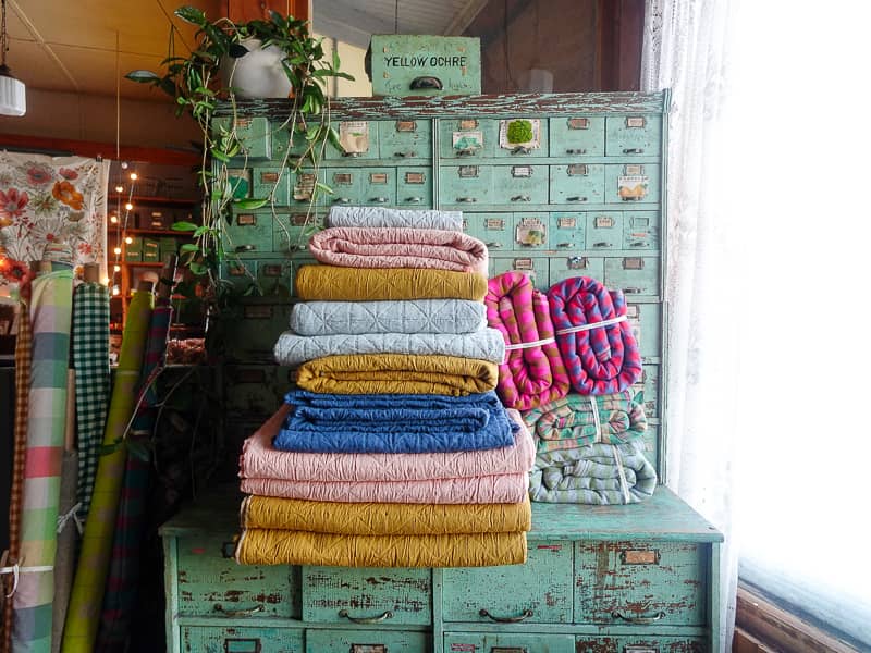 stacks of fabric on a vintage seed cabinet