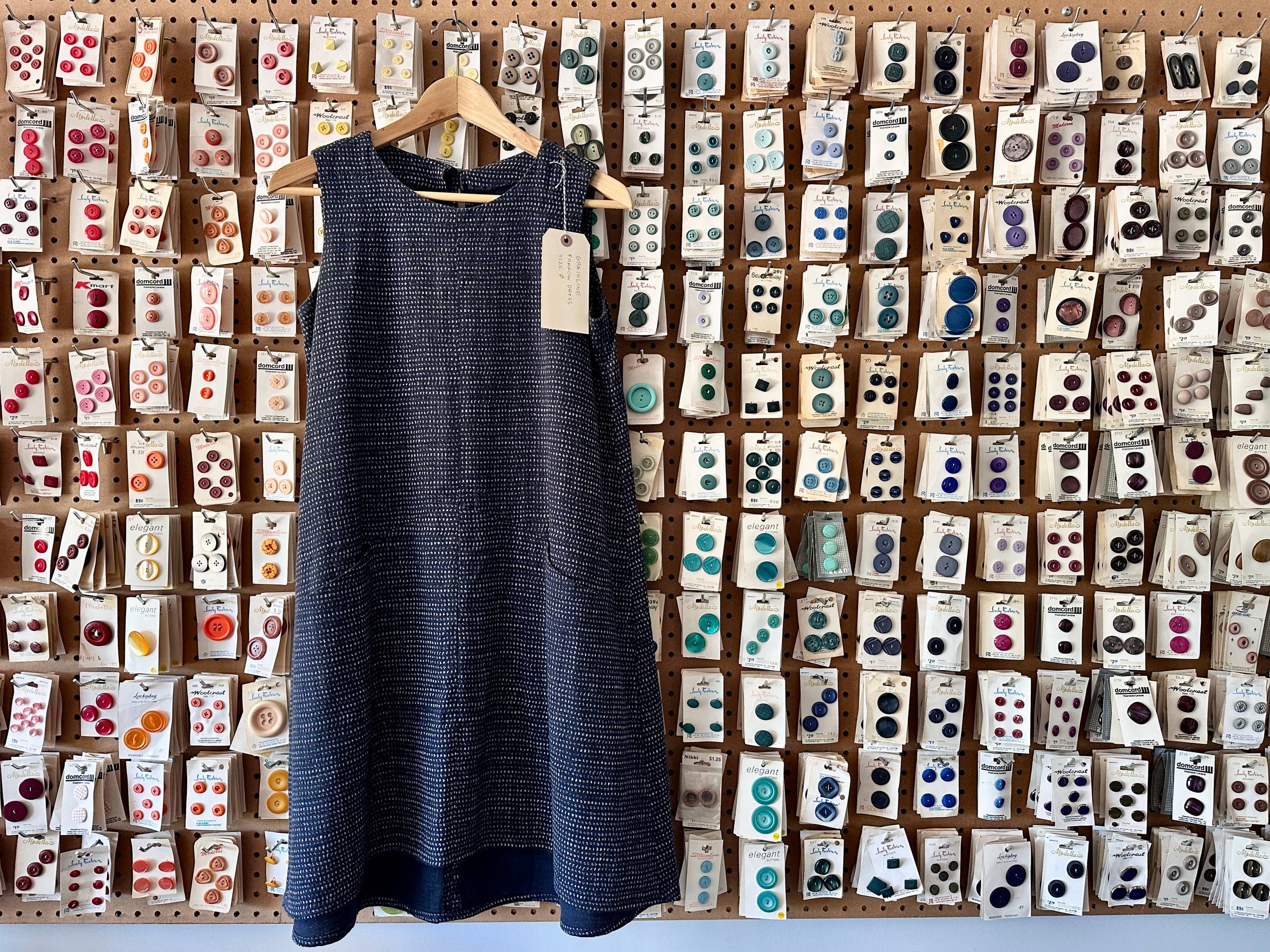 Indigo Farrow Dress Hanging on a button wall