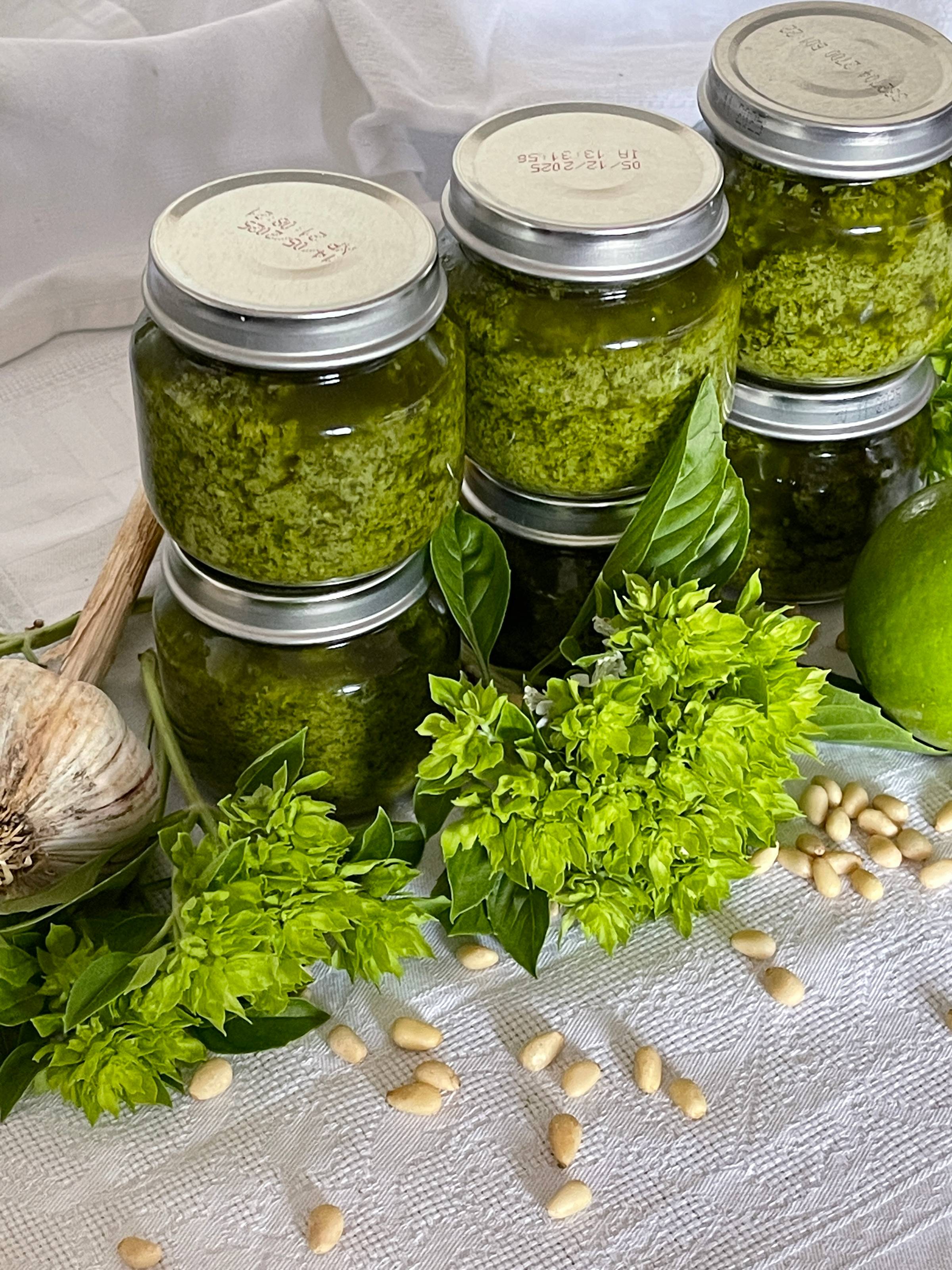 photo of 6 pesto jars stacked together with garlic and pine nuts on a table