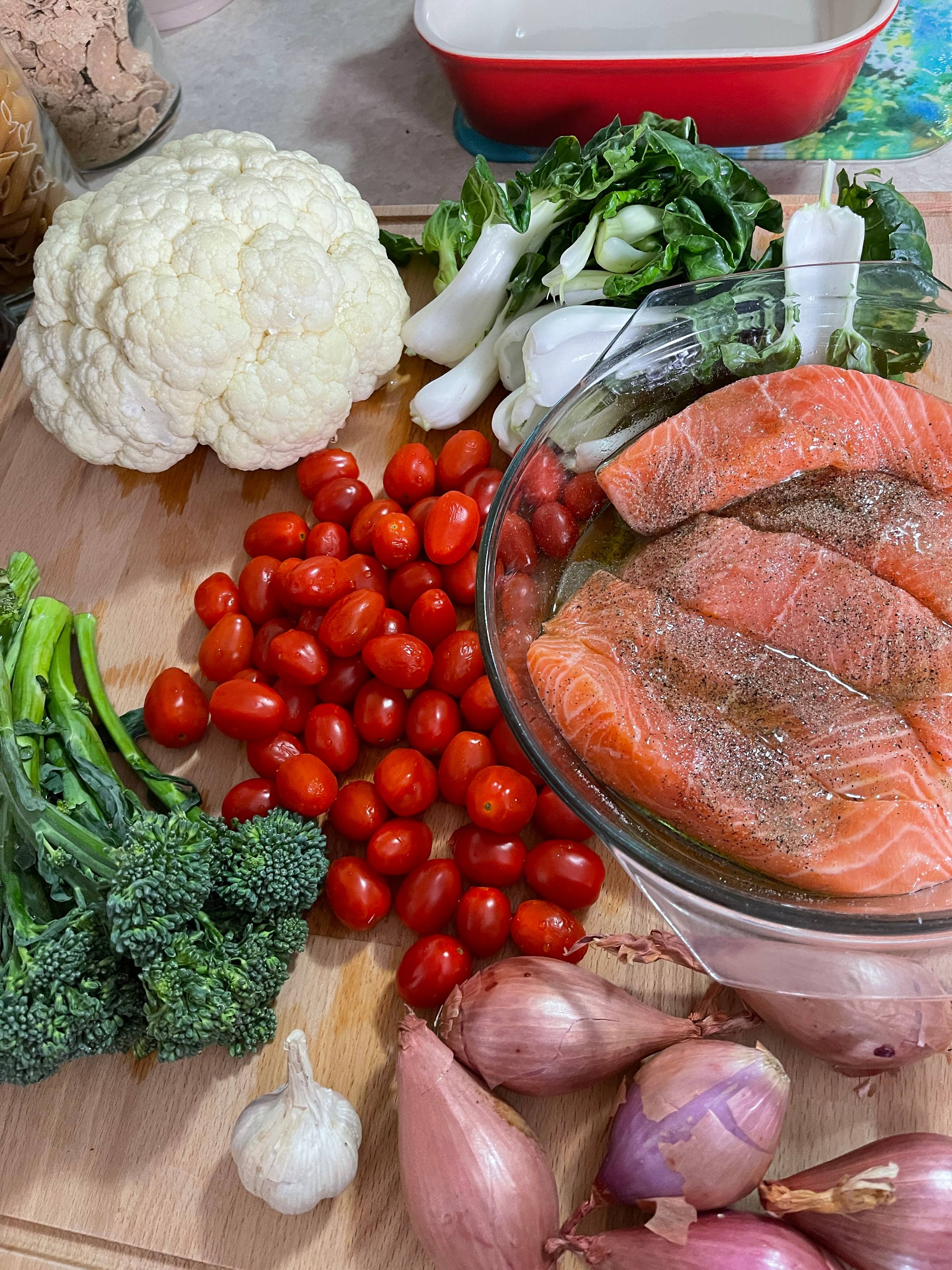 Rustic Mediterranean kitchen scene with a baked salmon fillet, roasted vegetables, olive oil drizzle, and fresh herbs on a wooden table — from Alma’s 5-Day Meal Plan.
