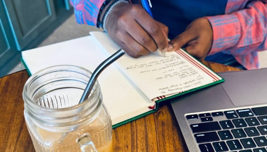 A man's hands are show writing in a journal