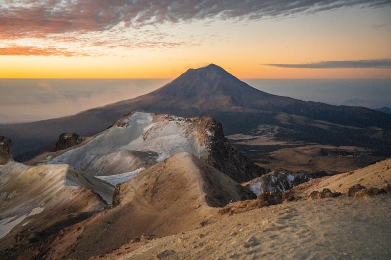 A view of a mountain with a sunset in the background