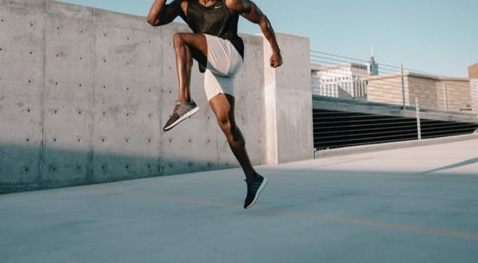 man in black tank top and white shorts jumping on mid air during daytime