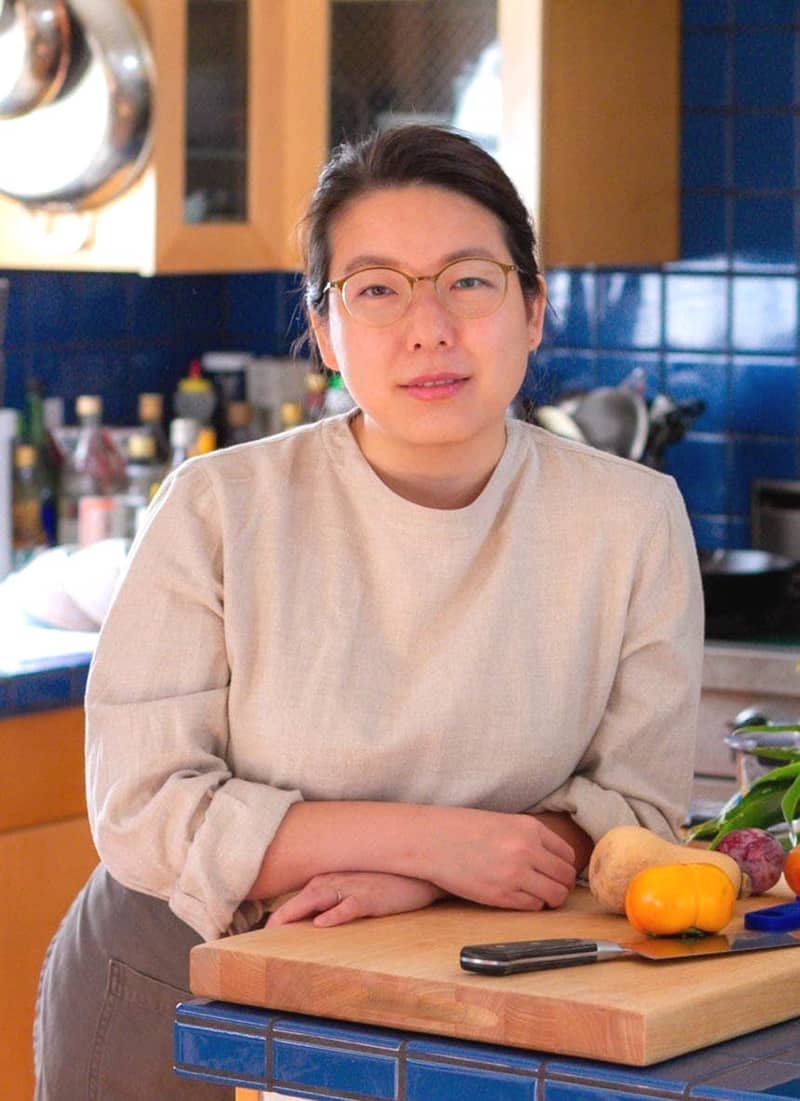 Cindy smiling while standing in a kitchen, leaning on the counter.