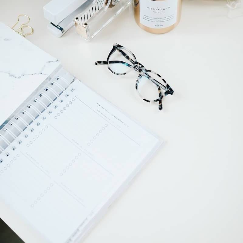 black framed eyeglasses beside spiral notebook