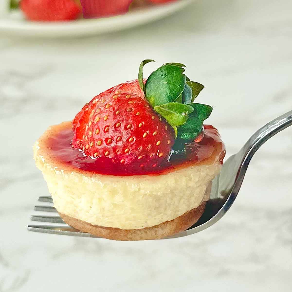 A mini strawberry cheesecake on a fork.