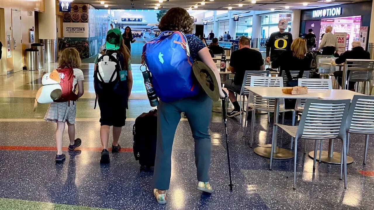 Women with a prosthetic leg walks while wearing a 35-liter carryon backpack on her back through the airport