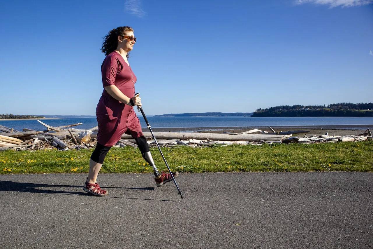 Amputee uses prosthetic leg and trekking pole to enjoy walking along a seaside trail