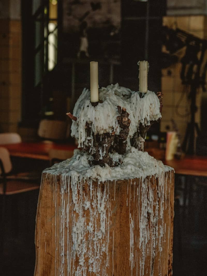Two candles in a wooden base covered in thick layers of dripping white wax