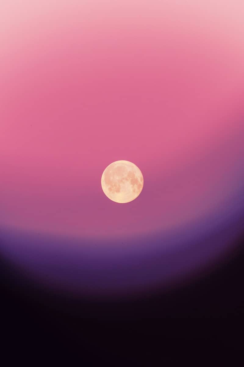 Full moon in a gradient pink and purple sky.