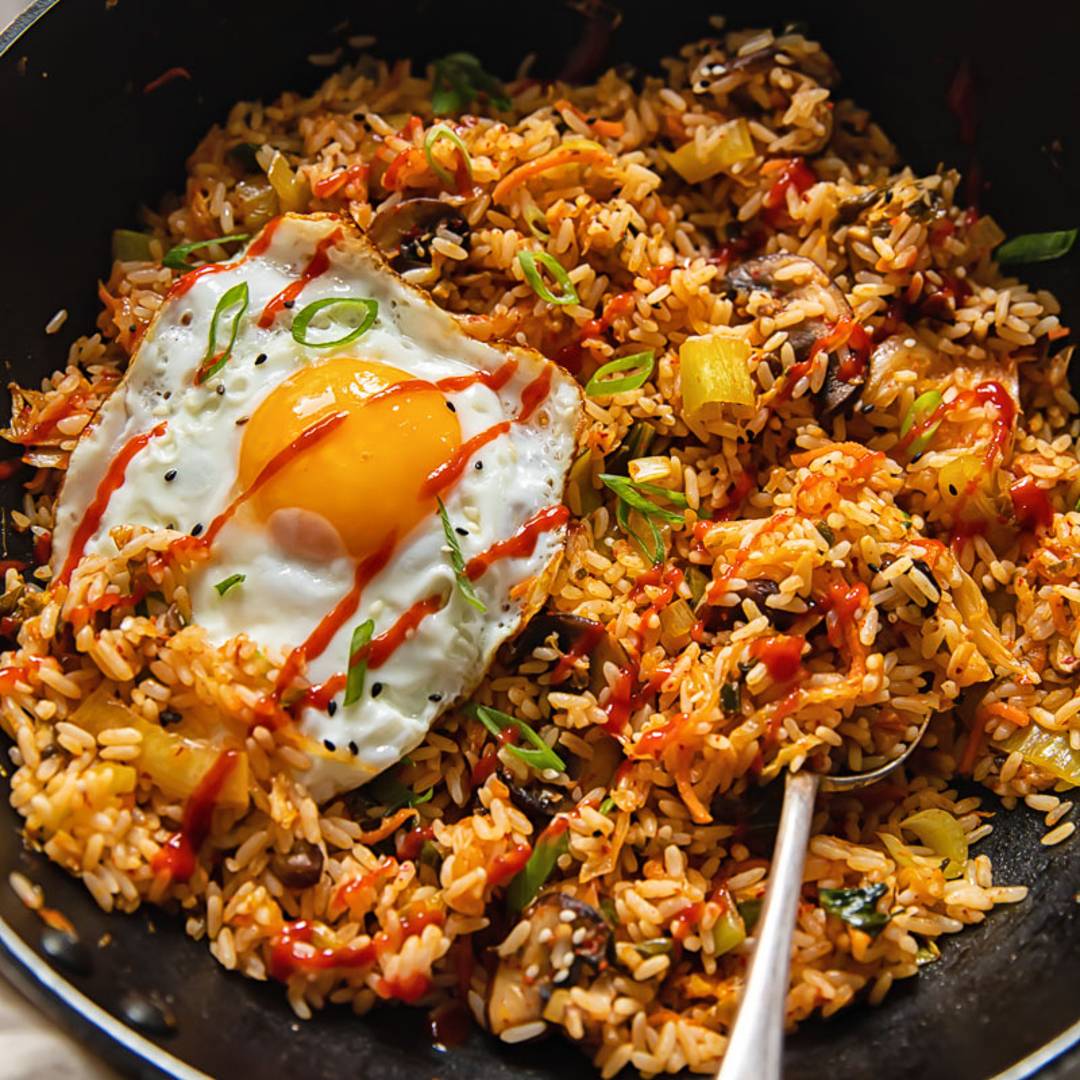 a black pan with fried rice topped by a fried egg with a serving spoon