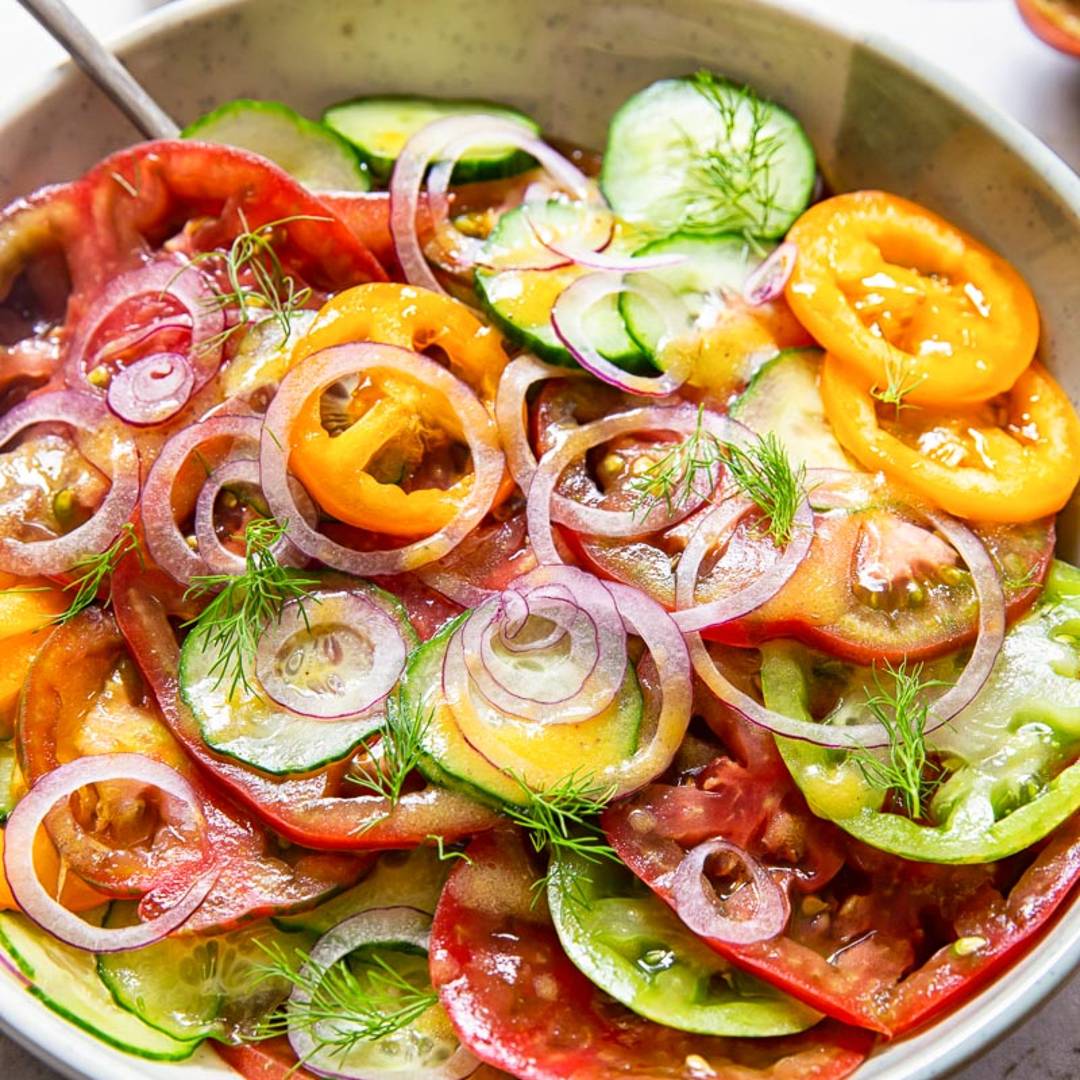 bowl of salad with colourful tomatoes and thinly sliced cucumber and onions