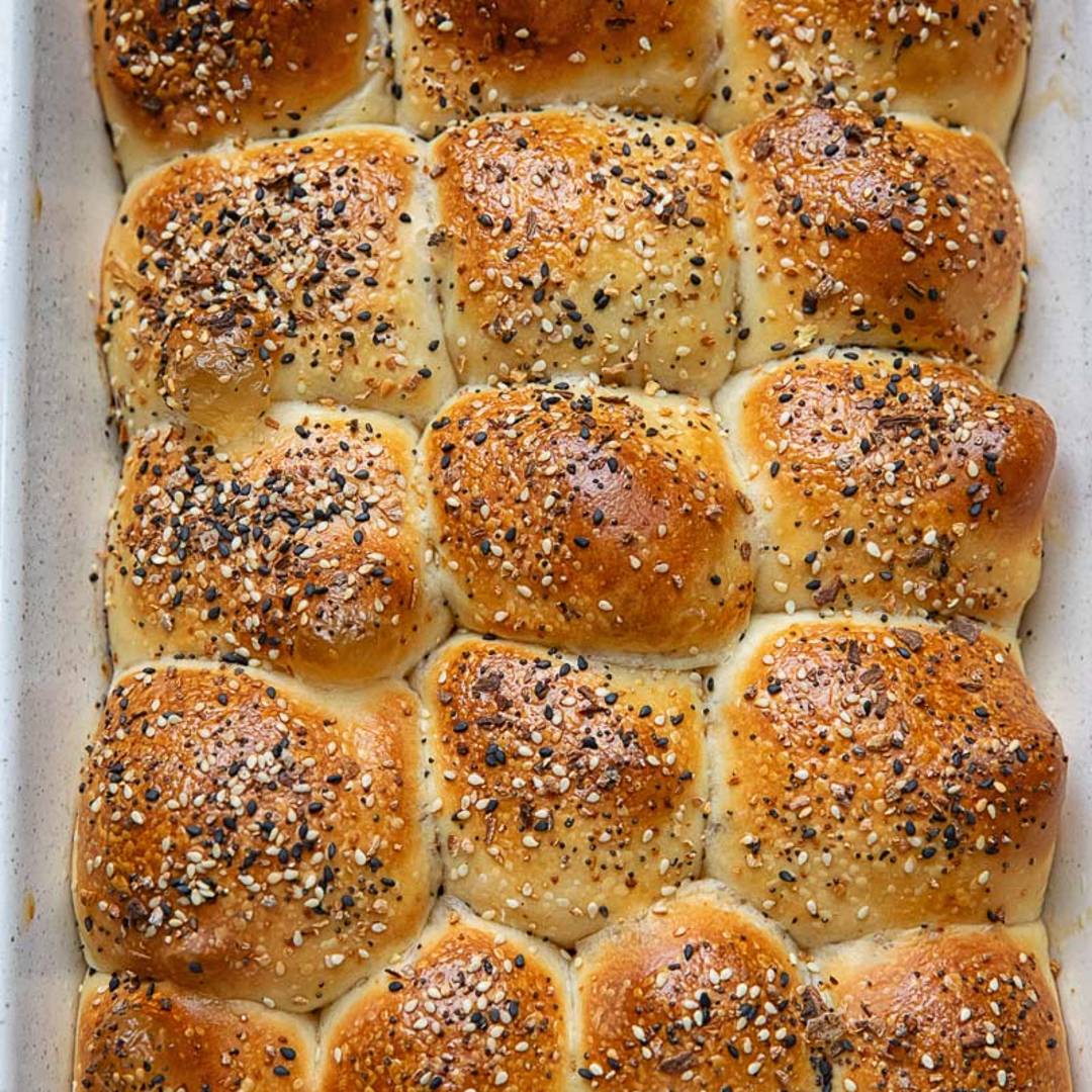 baking dish with dinner rolls topped with poppy and sesame seeds