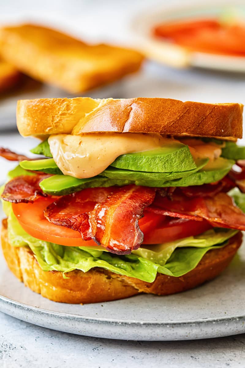 sandwich on a blue plate, made with lettuce, bacon, tomato and a sauce