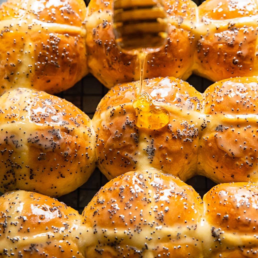 lines of hot cross buns with honey being drizzled on top