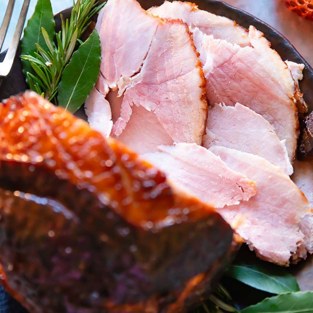 top down view of a glazed ham with slices lying in front of it