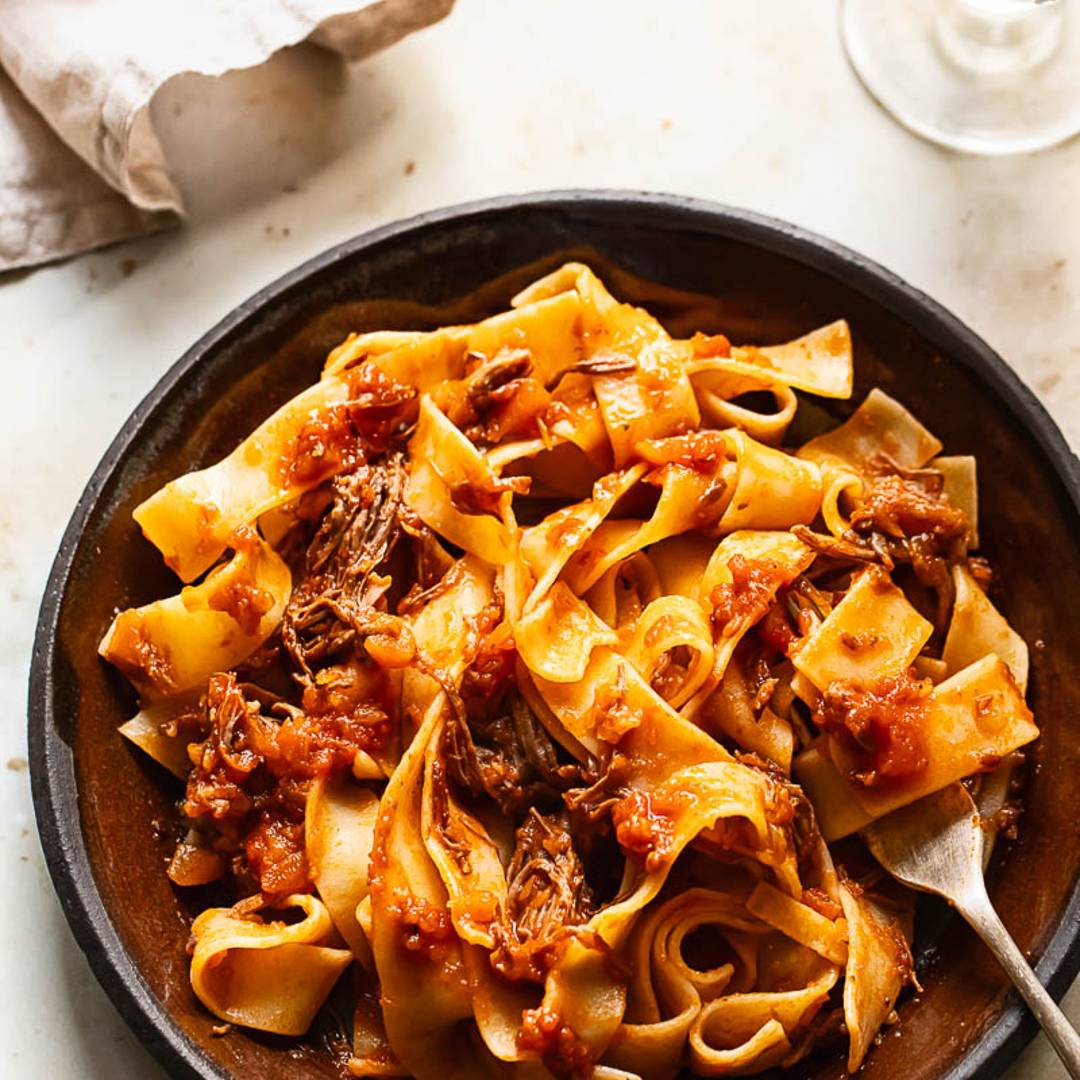 thick pasta with a red meat sauce and shredded parmesan cheese