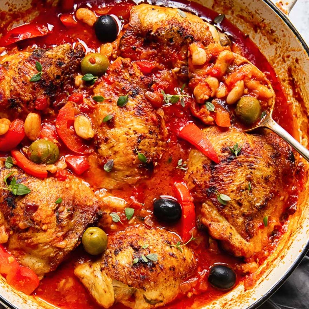 pan with chicken cooked in a red sauce with olives and other vegetables