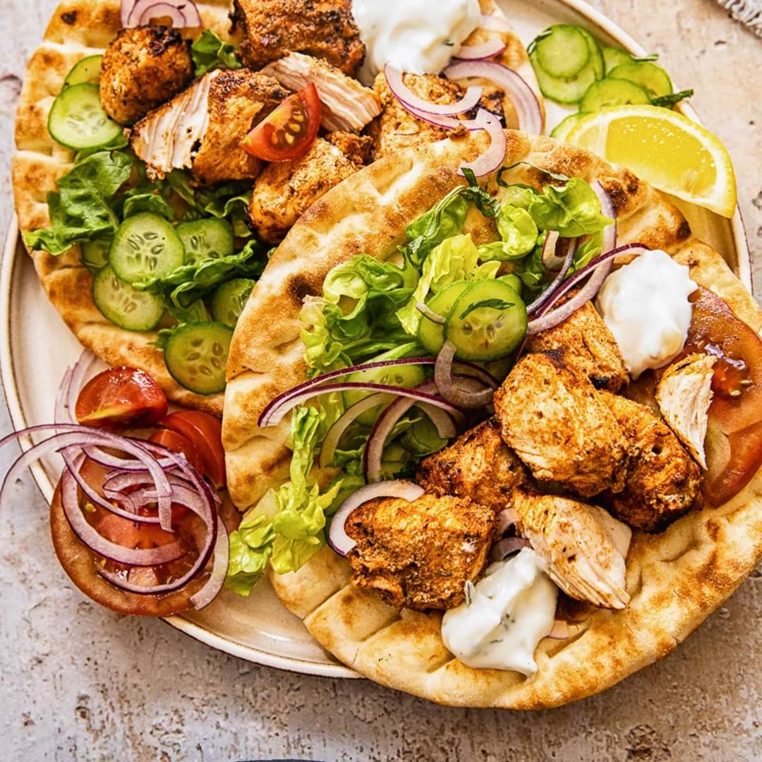 two flatbreads with chicken and vegetables on a light background