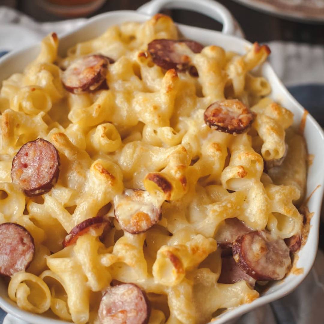 macaroni and cheese with sausage pieces in a white dish