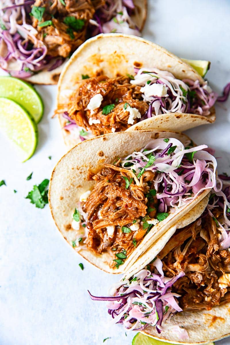 three tacos filled with pulled pork and strands of cabbage