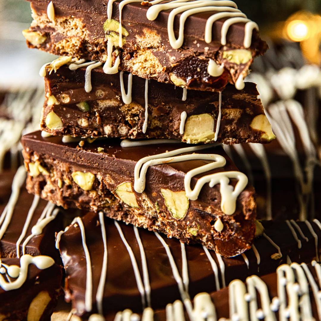 a stack of cookie bars with nuts and chocolate and a drizzle of icing