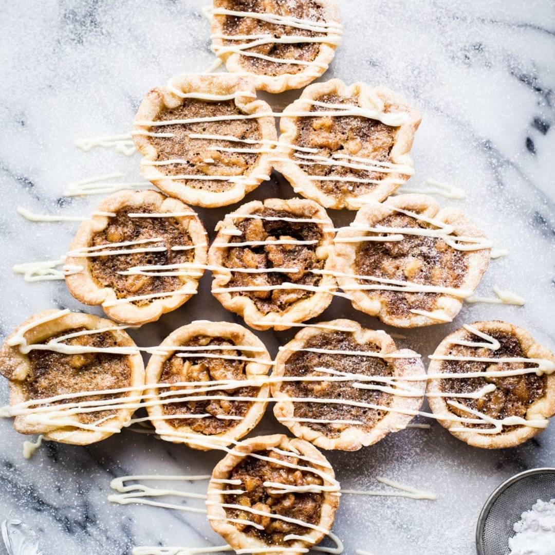 a series of tarts with a brown filling arranged like a Christmas tree on a marble background