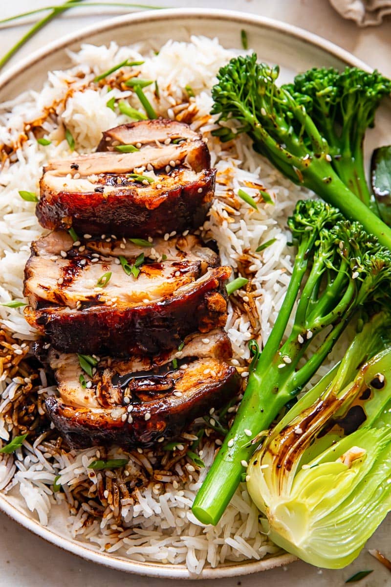 slices of pork belly on rice with broccoli and bok choy