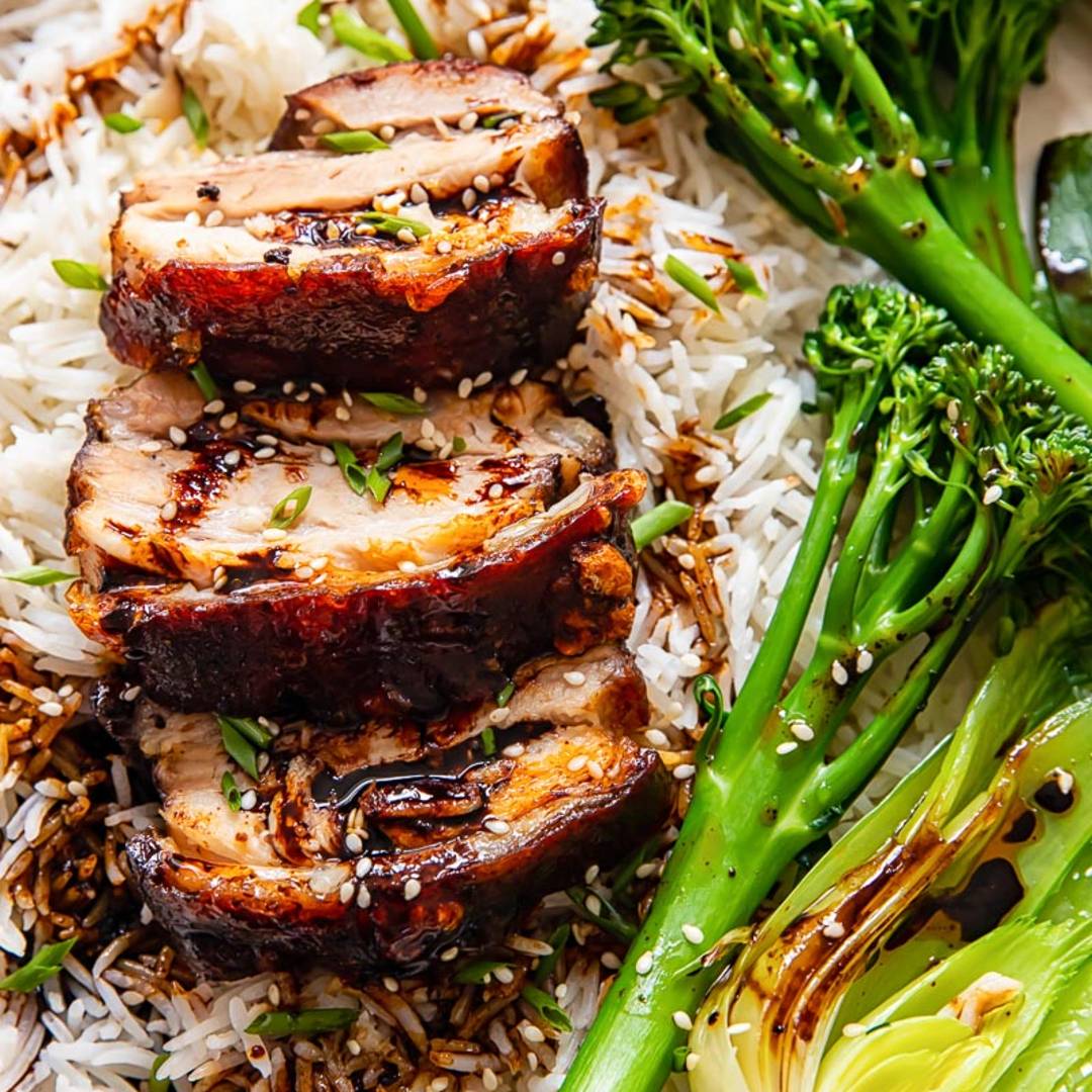 slices of pork belly on rice with broccoli and bok choy