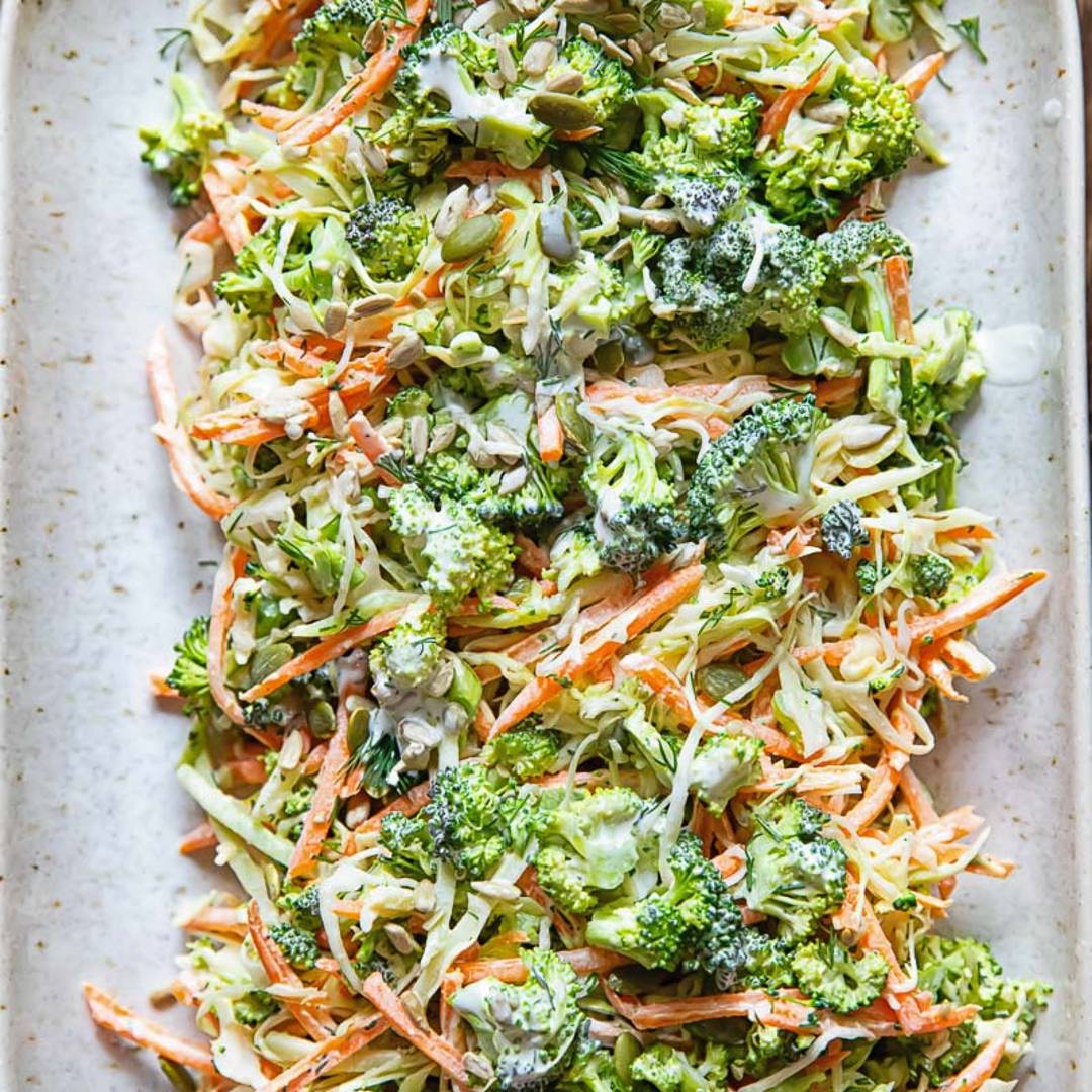 a large serving of broccoli slaw, with thin carrots and a light dressing, on a oval serving platter
