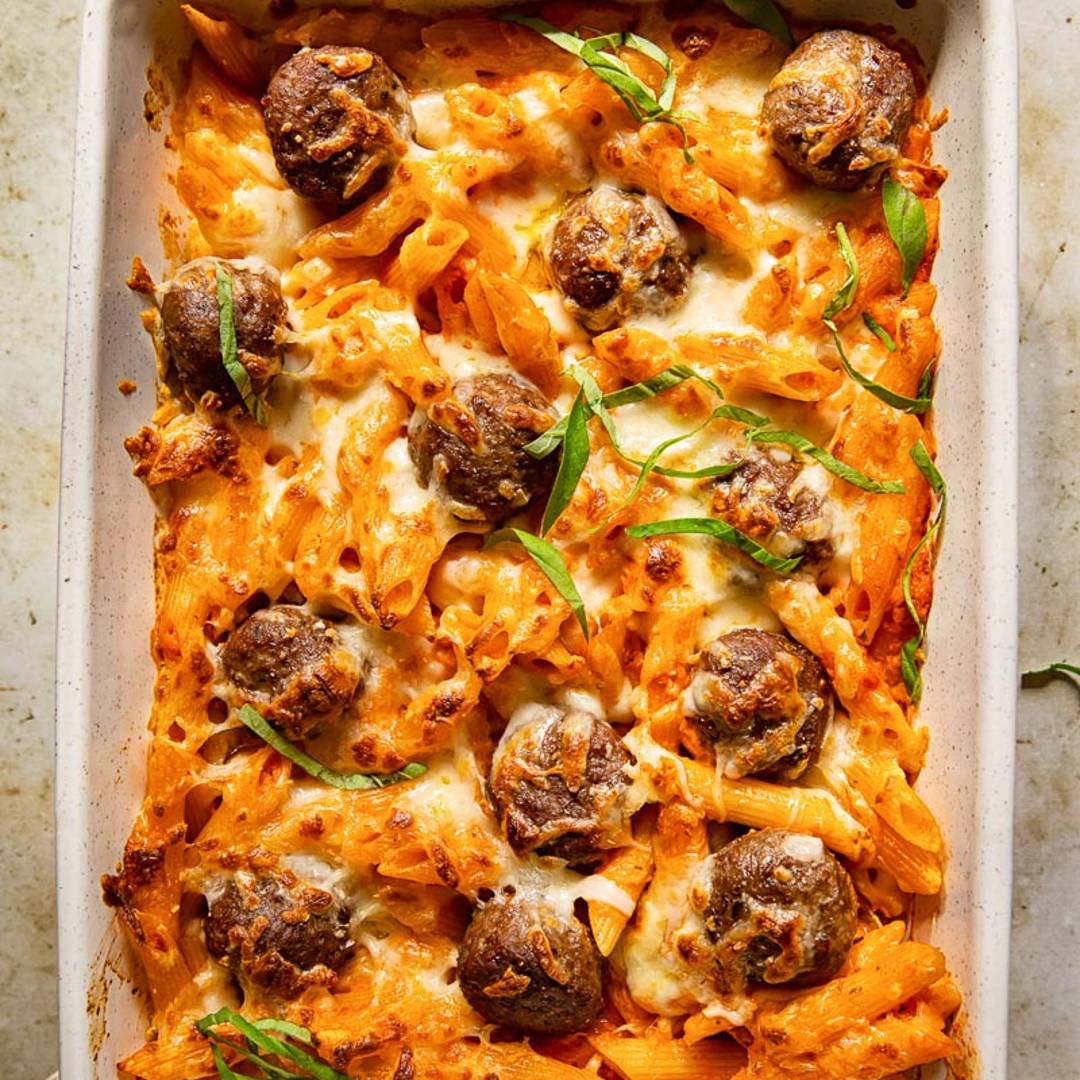 baked pasta in a pan with meatballs and slices of basil
