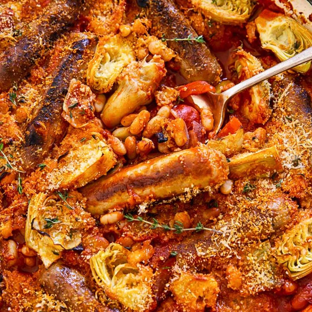 close up of a red casserole with sausages and beans visible