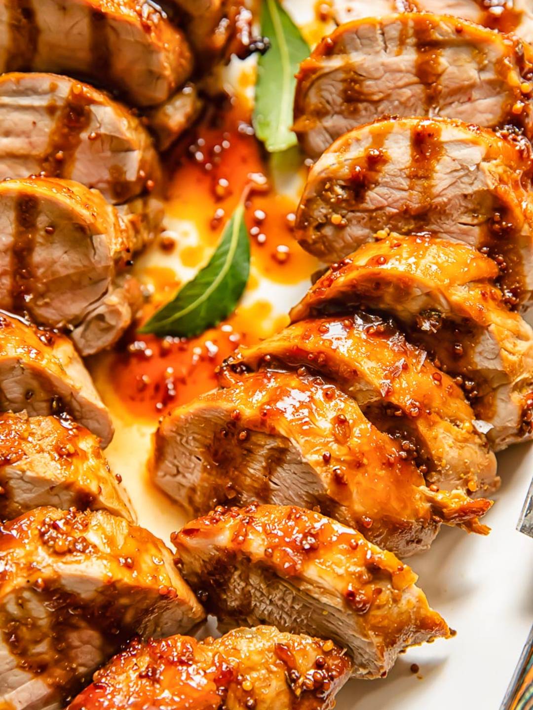 Close up image of pork tenderloin slices with a golden sauce.