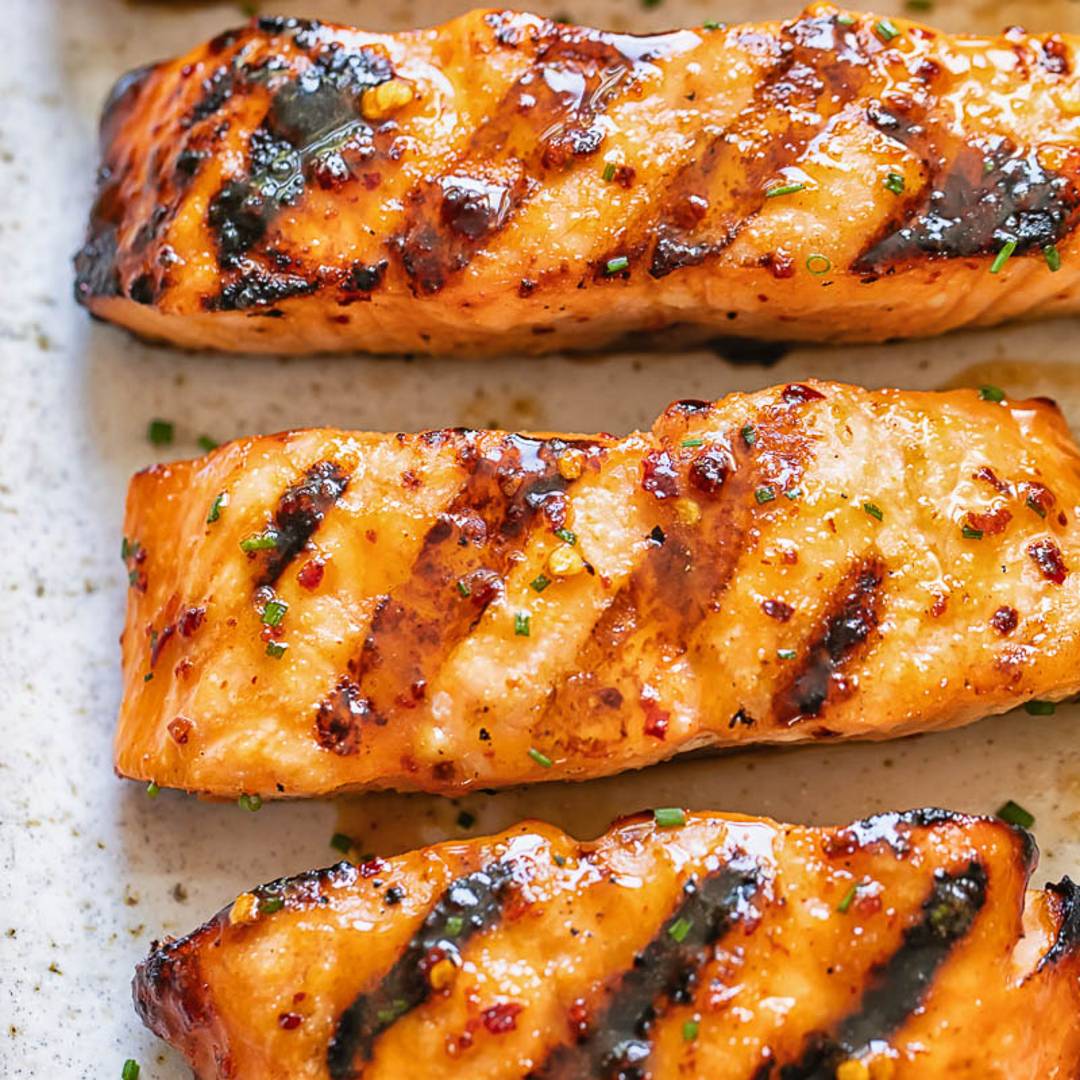 strips of salmon with a glistening glaze with grill lines on a light background