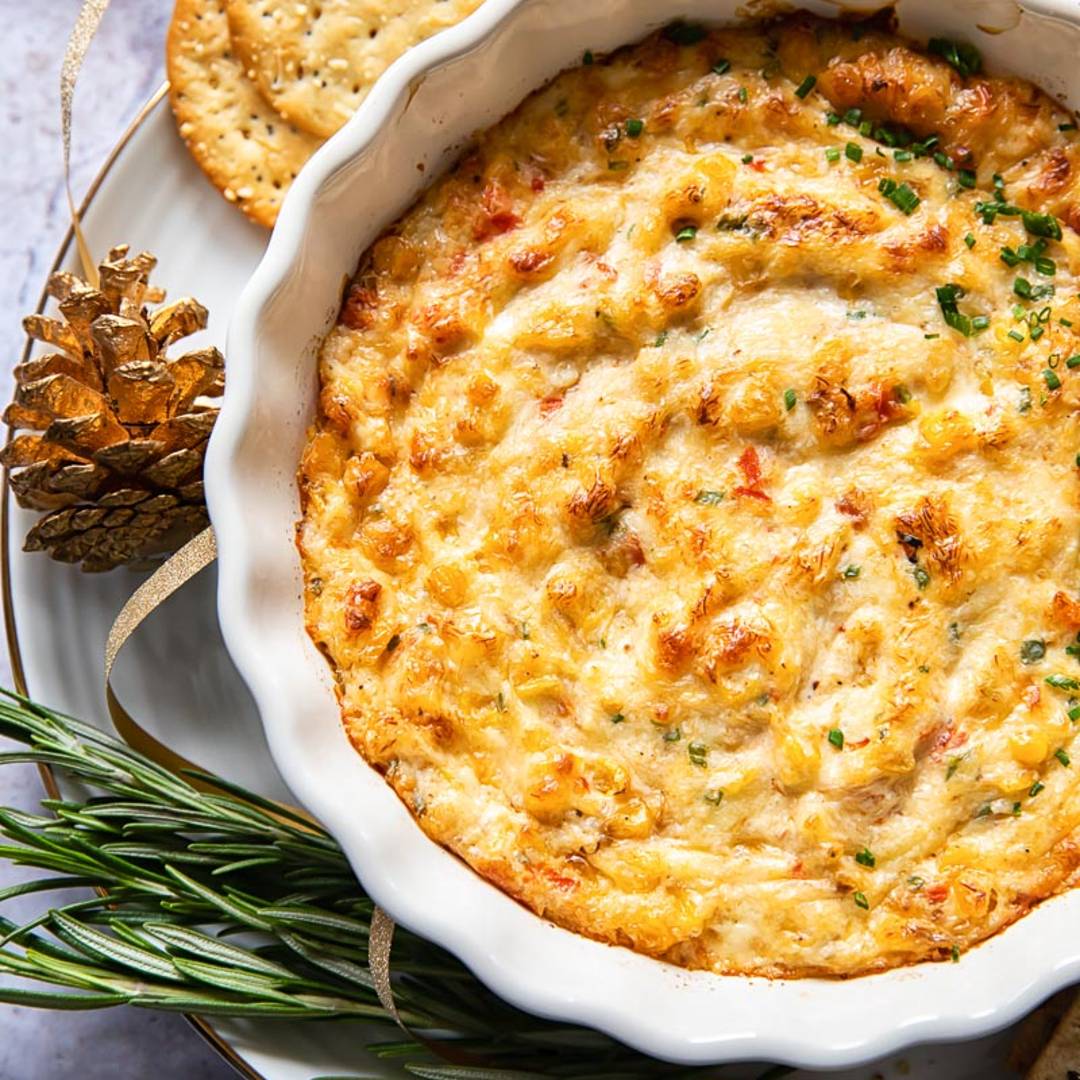 top down view of a dip in a small bowl on a plate with rosemary and crackers