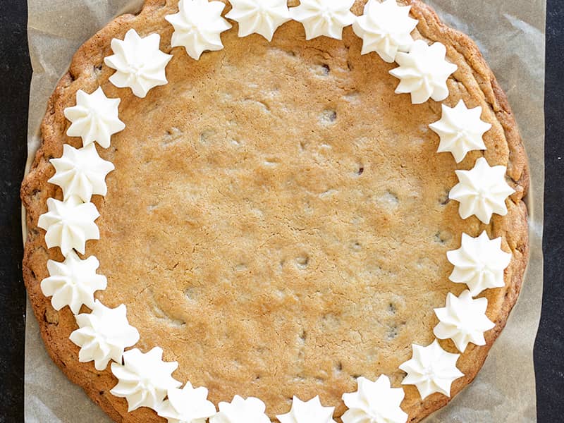 overhead image of large cookie cake with border of white piped star-shaped frosting