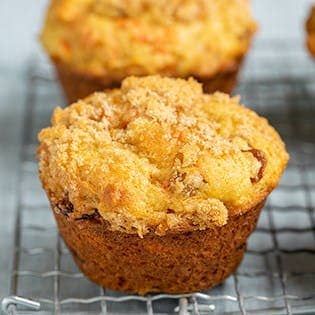 two carrot muffins on wire rack on blue cloth
