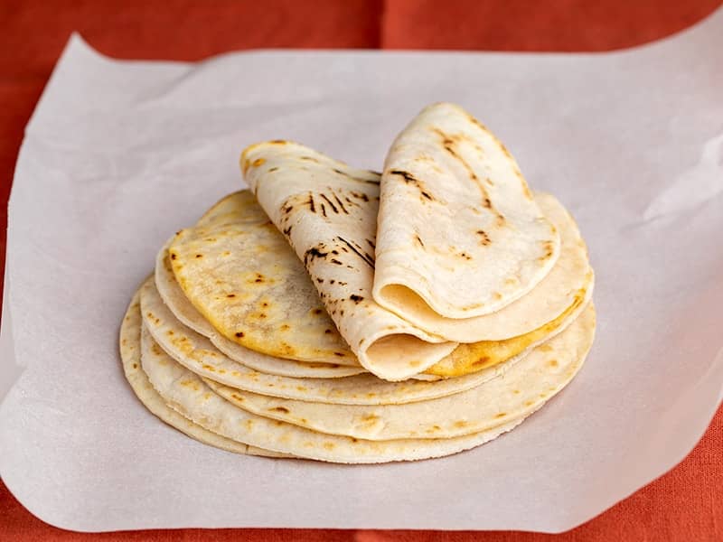 stack of cassava flour tortillas with two folded on top, on white paper