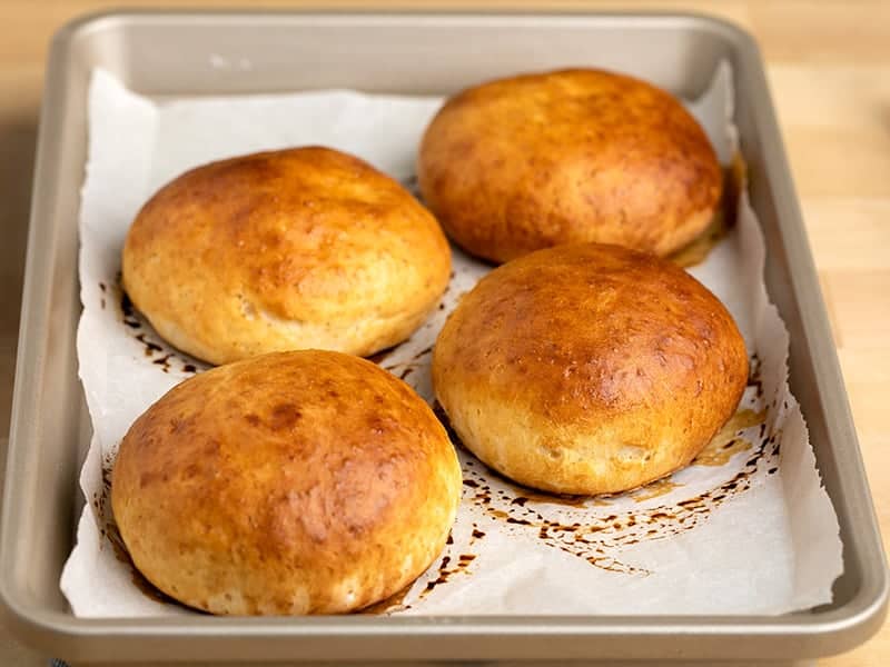 4 Hawaiian rolls on white paper on a baking tray