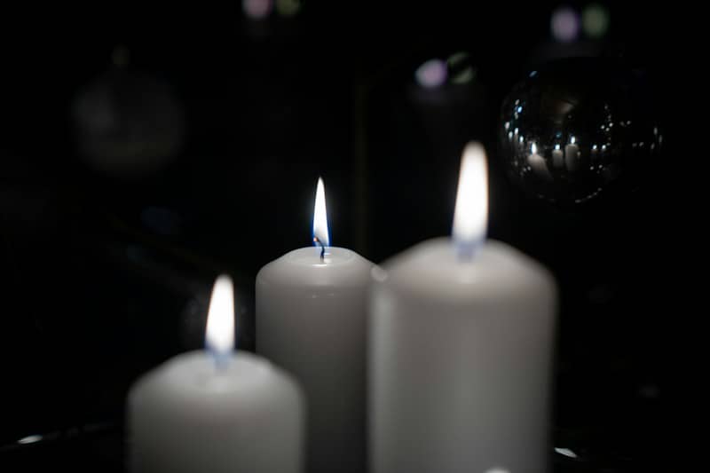Three white candles sitting on top of a table