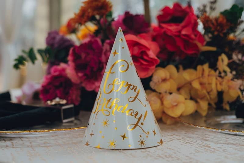 Party hat with "happy birthday" message and flowers.