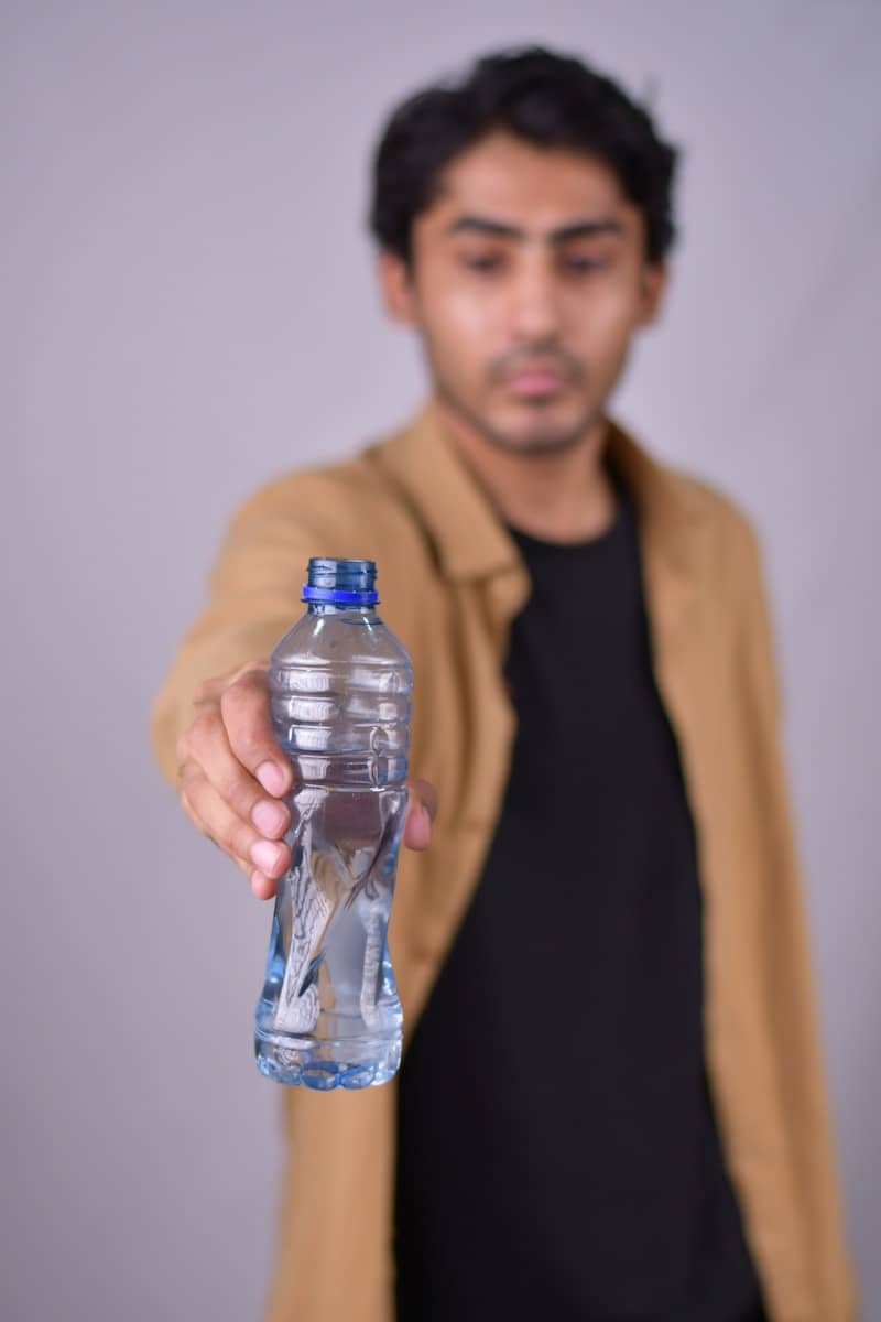 your book boyfriend holding a bottle of water in his outstretched hand because you need to take better care of yourself.