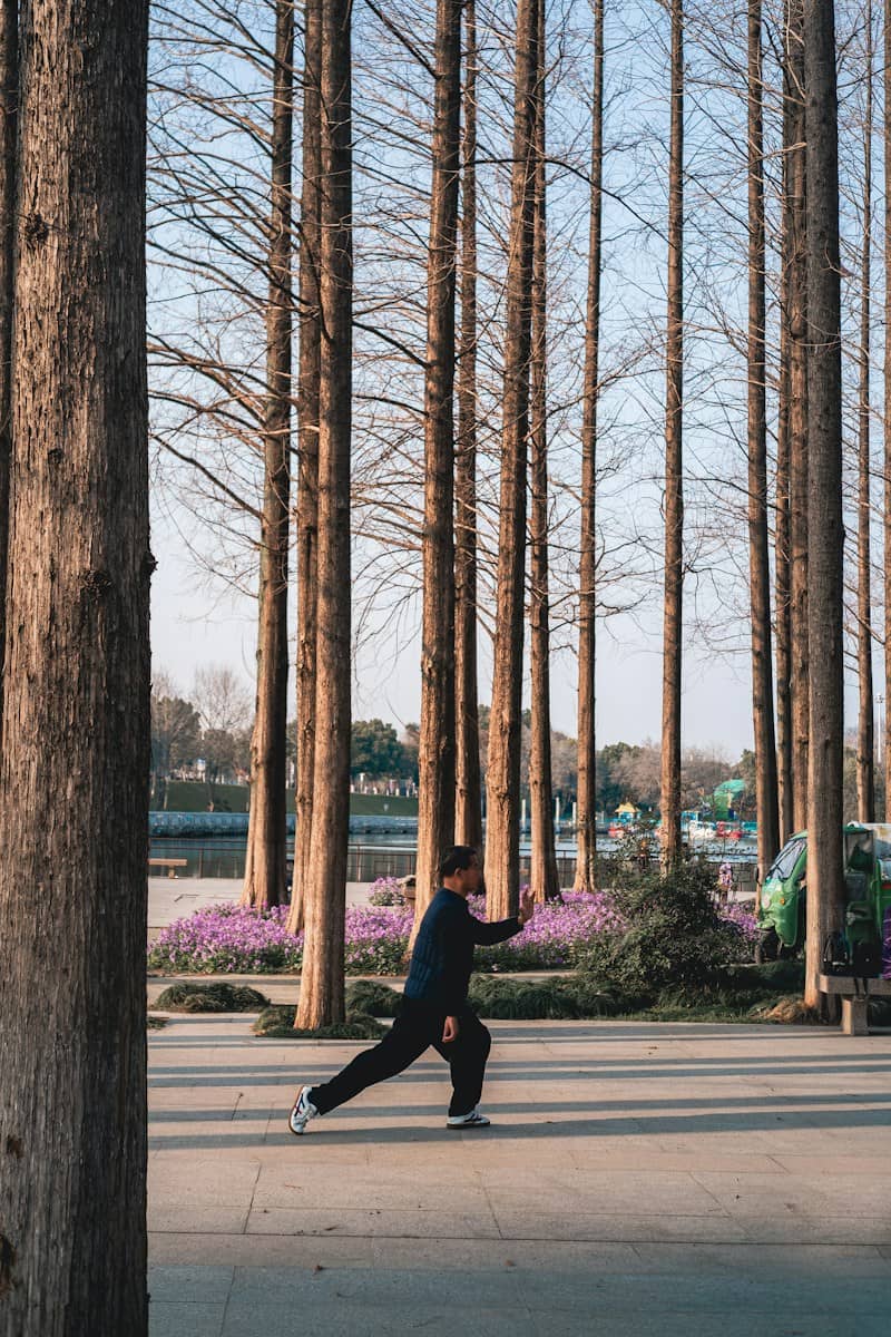 Man practicing tai chi among tall trees